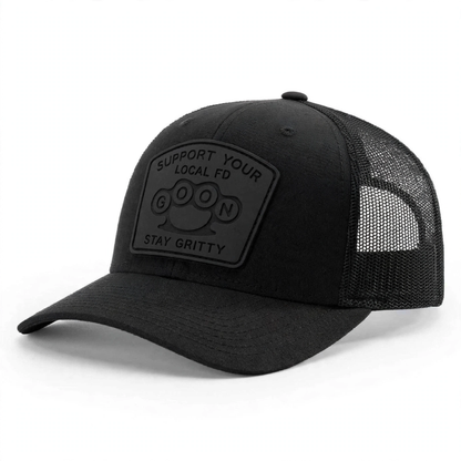 Blackout lifestyle alt: Man wearing blackout GOON Support Your Local FD Richardson 112 trucker hat driving vintage Ford truck, black on black murdered out silicone patch Firefighter Gift
